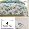 A white duvet cover featuring a watercolor floral pattern in teal and grey tones, shown on a bed.