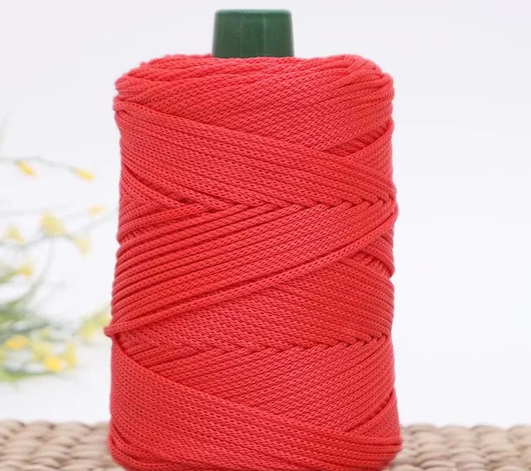 A spool of bright red crochet ice rope with a dark green cap, lying on a woven surface.