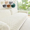 A white quilted anti-slip sofa cushion displayed on a light-colored sofa with various colored fabric swatches.
