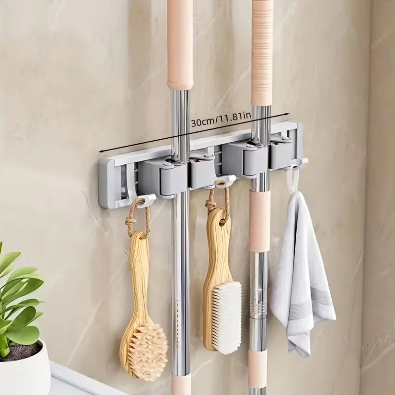 Wall-mounted metal holder for mop and broom with detachable hooks, featuring pink and silver poles.