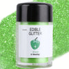 A glass jar of green edible glitter powder labeled Edible Glitter, resting on a bright green glitter background.