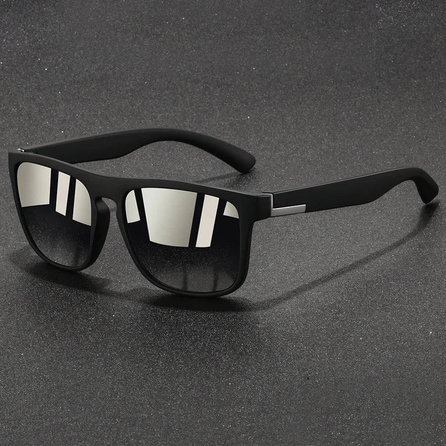 Un par de gafas de sol cuadradas negras vintage sobre una superficie texturizada gris oscuro.