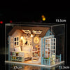 A detailed miniature wooden dollhouse featuring furniture and architectural elements displayed in a clear box.