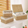 A stack of natural woven rattan storage baskets and a larger basket on a white table.