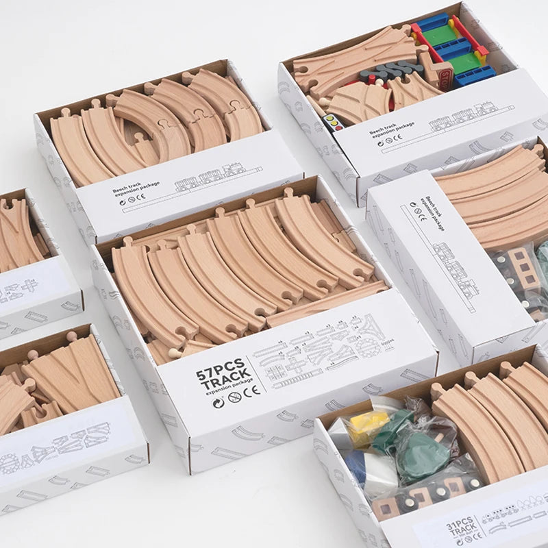 A collection of wooden train track expansion packs in various sizes and colors displayed in cardboard boxes.