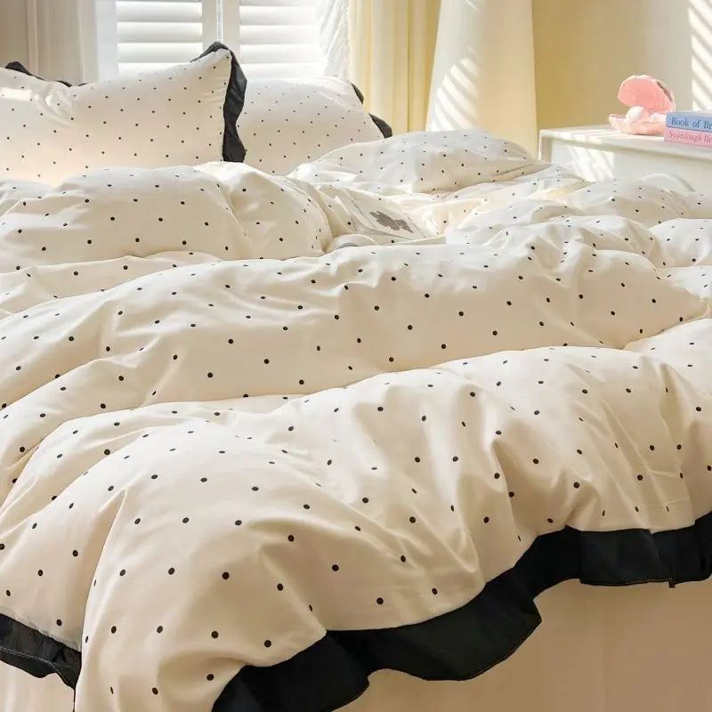 White polka dot bedding set with duvet cover and pillowcases displayed on a bed.
