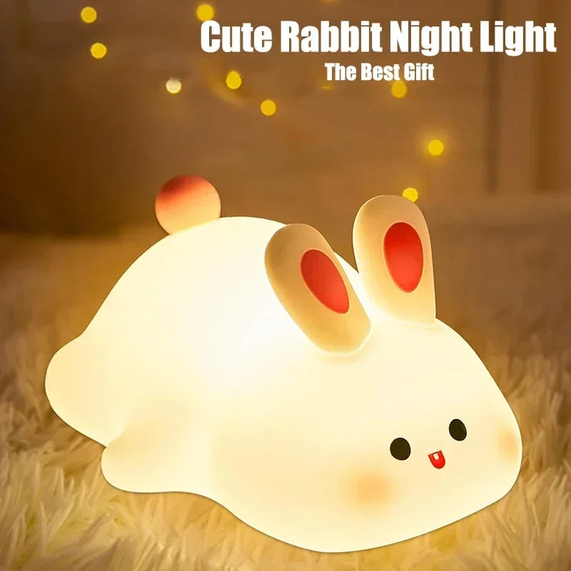 A white rabbit night light with pink ears glowing softly on a fluffy surface.