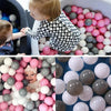 A close-up view of a large quantity of colorful soft play balls in various shades of pink, white, and gray.