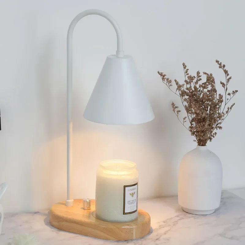 A white electric candle warmer lamp with a conical shade and wooden base sits on a marble surface.