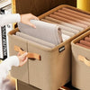 A hand is opening a beige fabric storage box filled with rolled, light-colored textiles for closet organization.