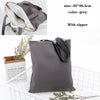 A grey foldable canvas tote bag with a zipper and natural twine detail is shown next to its packaging.
