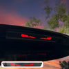 A close-up of a black car's rear light featuring a red cartoon devil eyes decal.
