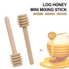 A wooden honey dipper stick and a jar of golden honey on a yellow surface.