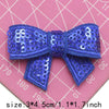 A royal blue sequin bow patch for DIY crafts displayed on a pink grid background.