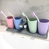 A silicone faucet splash mat with multiple colored cups and brushes is displayed on a gray countertop.