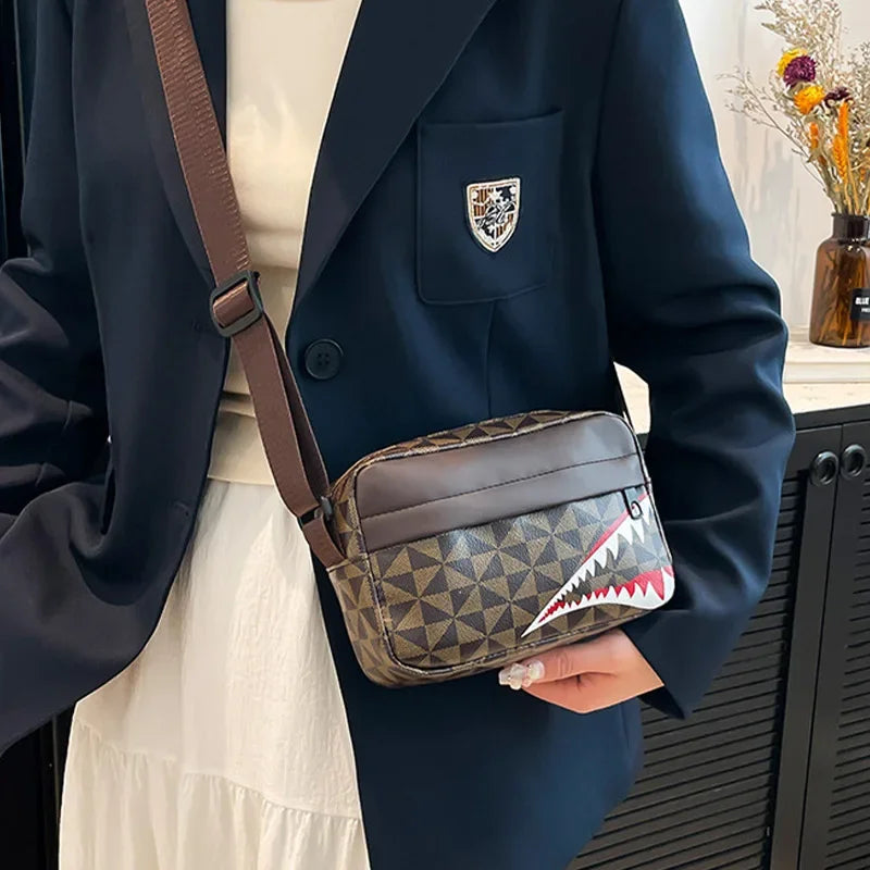 A dark navy blazer is shown holding a brown leather crossbody bag with a shark-mouth design.