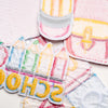 A collection of colorful iron-on patches featuring school-themed designs and stripes on pink and yellow fabric.