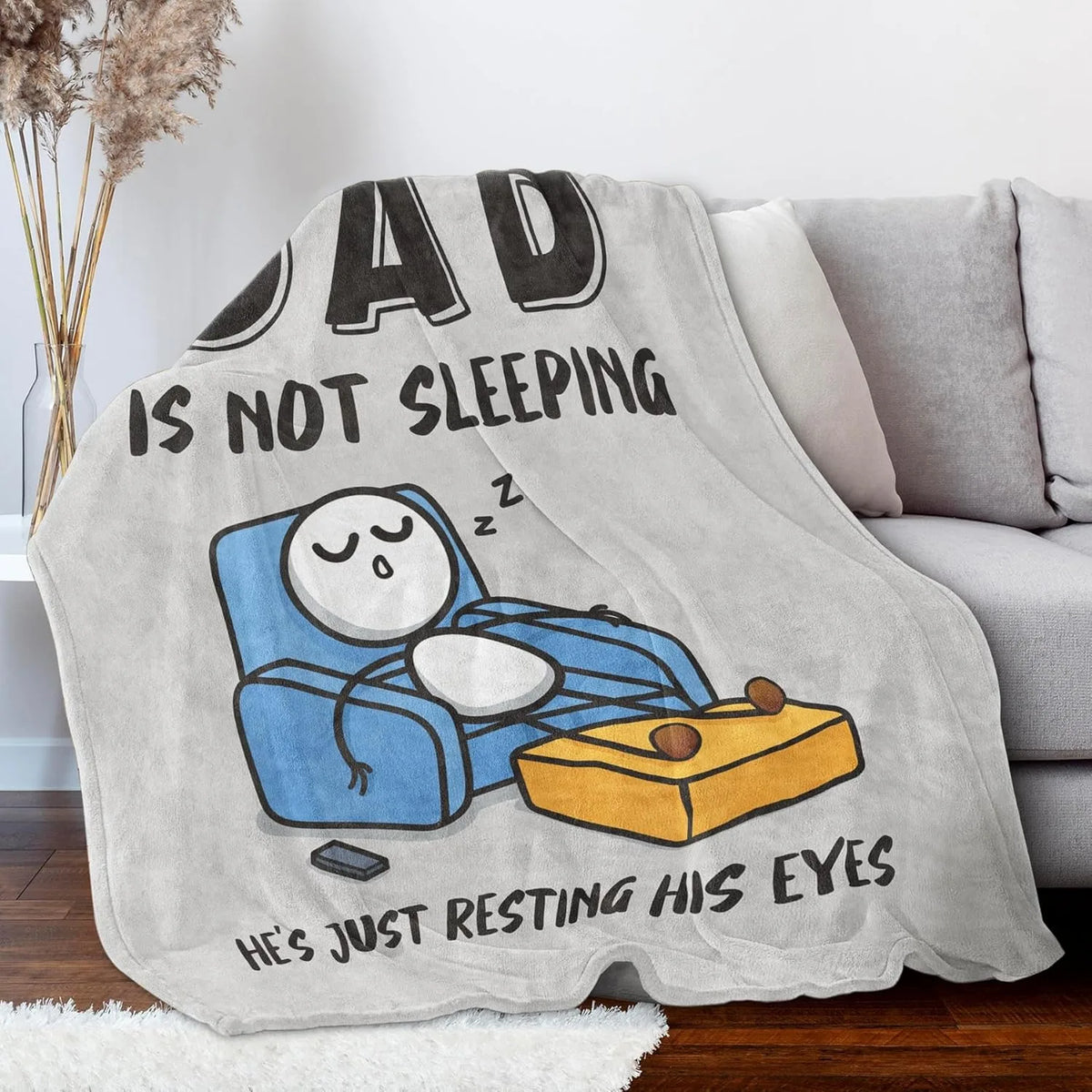 A gray fleece throw blanket featuring a graphic of a sleeping dad resting his eyes.