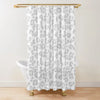 A white leopard print shower curtain hanging from a gold rod.
