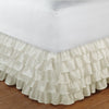 Cream ruffled elastic bed skirt wrapping around a mattress to hide under-bed space