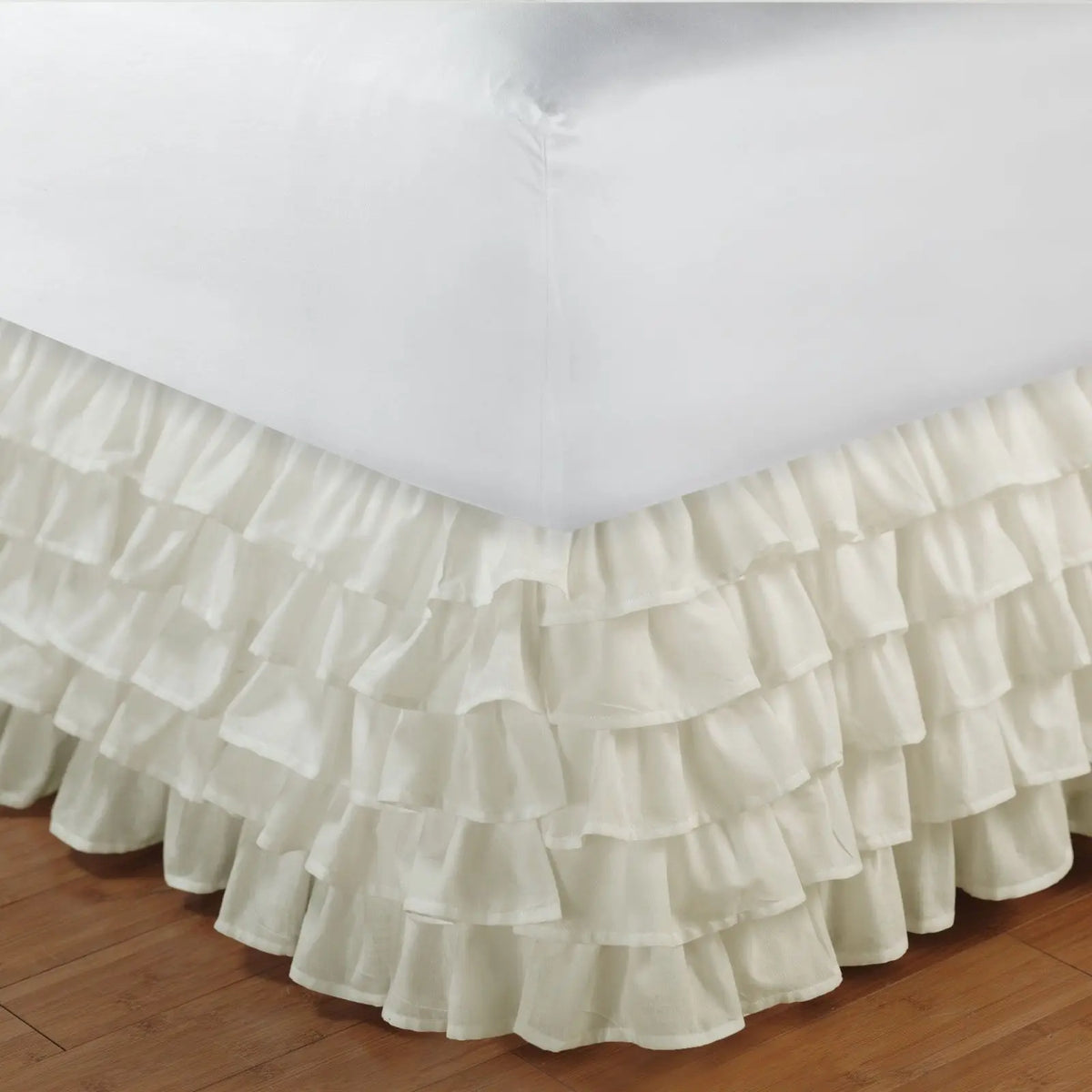 Cream ruffled elastic bed skirt wrapping around a mattress to hide under-bed space
