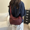 A woman is holding a dark burgundy leopard print crossbody bag with red trim.