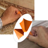 A hand is using an orange silicone tile grout filling tool to repair a seam in a tiled wall.