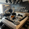 Silber- und schwarze Ballons schreiben 'Happy Birthday' mit großen Ziffern 2 und 1