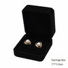 Black velvet jewelry box containing a pair of gold-toned pearl earrings.