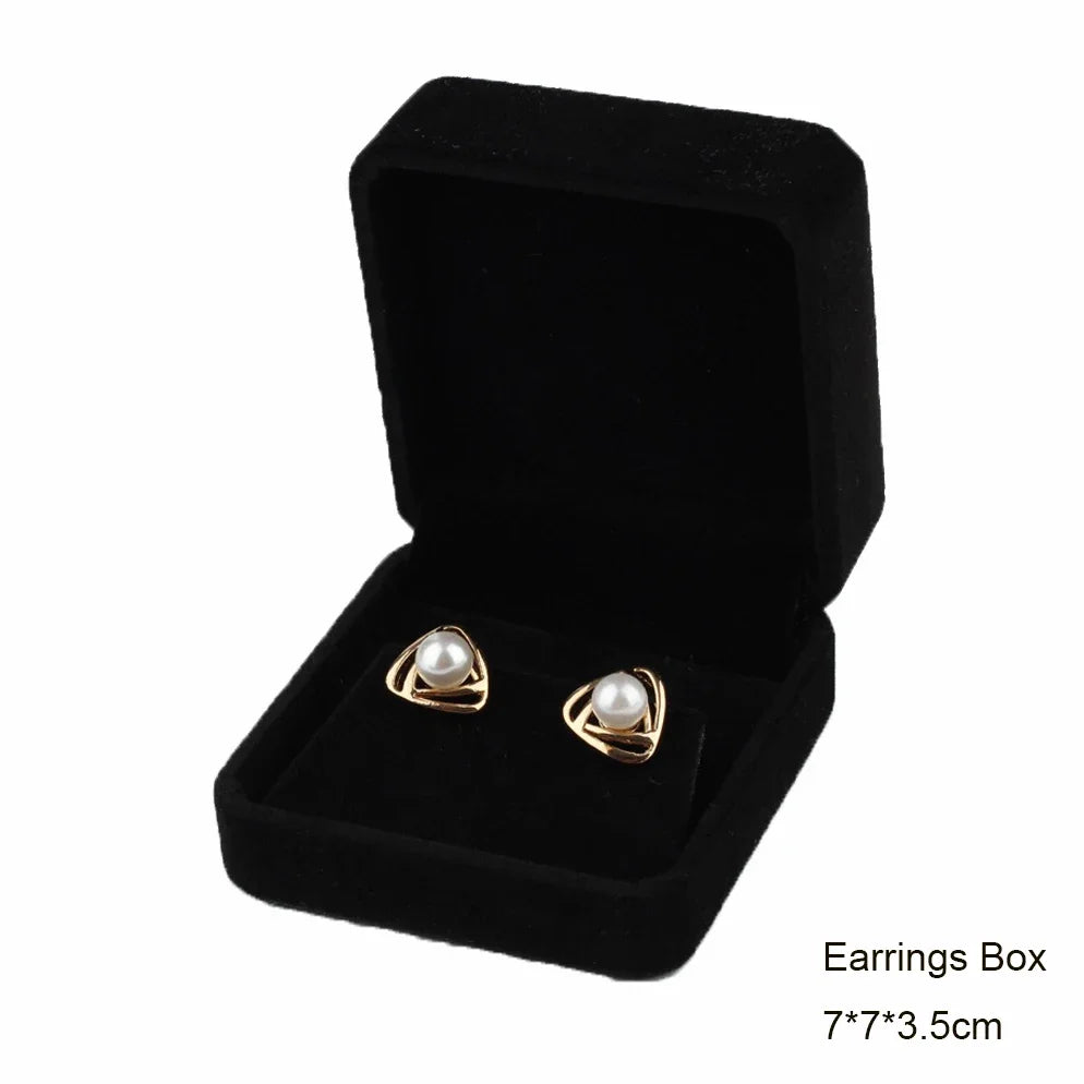 Black velvet jewelry box containing a pair of gold-toned pearl earrings.