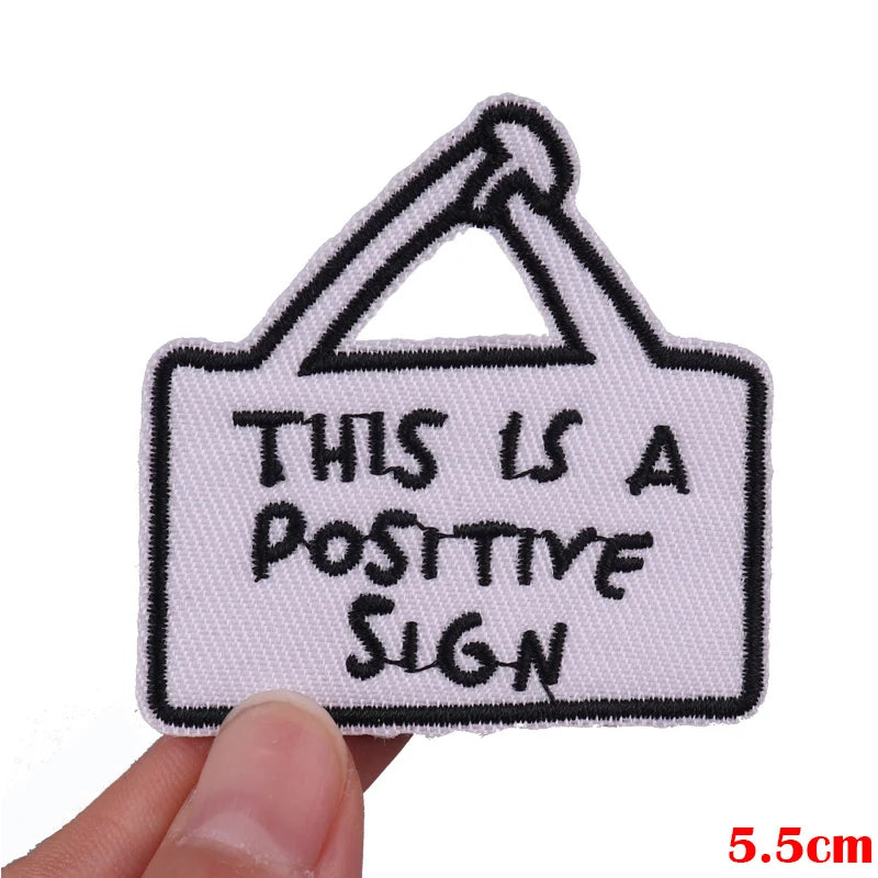 A white embroidered sign patch with black text that reads This is a positive sign.