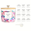 Clear glass storage container with a lid filled with colorful laundry pods and various laundry accessories.