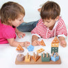 Two toddlers interact with wooden sorting and stacking toys including triangles, cubes, and cylinders.