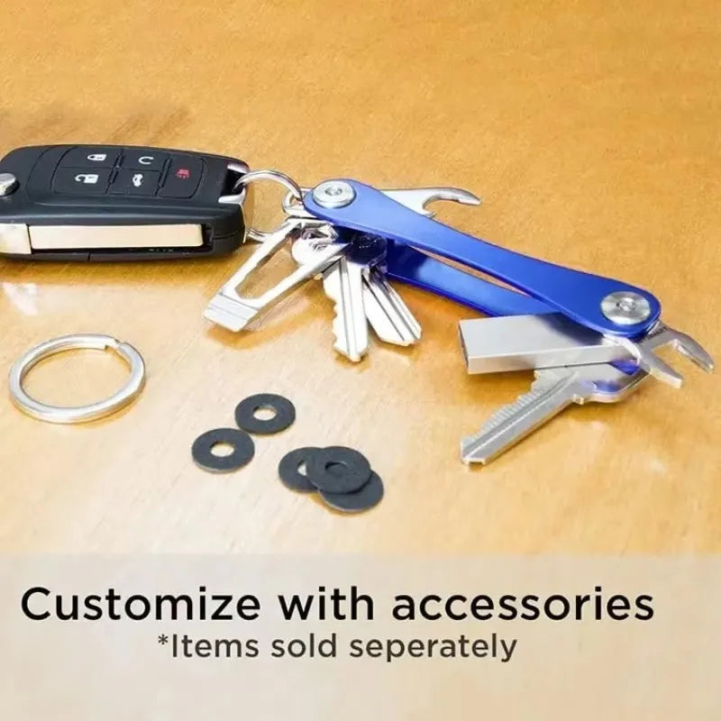 A blue aluminum key clip with a carabiner hook and various metal keys and accessories on a wooden surface.