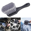 A black compact brush set with a silicone head is shown cleaning a car wheel and tire.