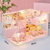 A detailed miniature wooden dollhouse building kit featuring pink and white furniture and interior decor.