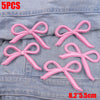 Five pink embroidered bow iron-on patches displayed on a denim fabric.