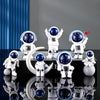 A collection of handcrafted astronaut figurine resin spacemen desk decor displayed on a black surface.