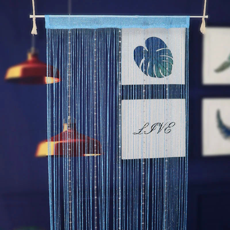 A blue beaded string curtain hangs vertically, featuring a white rectangular sign with the word LIVE and a blue leaf design.
