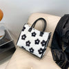A black and white faux fur leopard print tote bag resting on a light-colored sofa.