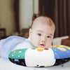 A baby is lying on a high contrast tummy time pillow with colorful designs.