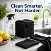A stack of black microfiber cleaning towels next to a kitchen sink and lemon on a white countertop.