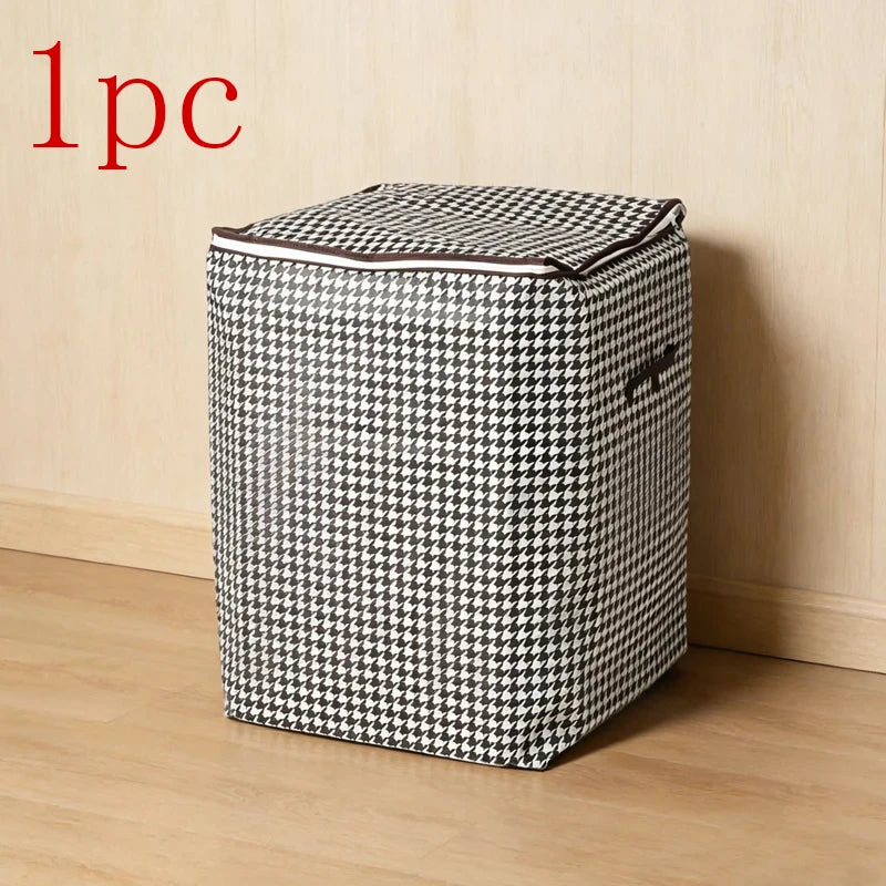 A single foldable quilt storage bag with a black and white houndstooth pattern resting on a wooden floor.
