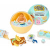 A yellow bowl contains a baby doll and miniature food accessories, next to a packaging box and a Miniverse Real Baby kit.
