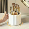 A white cylindrical organizer holding various gold makeup brushes and tools, shown from the side.