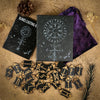 A set of wooden rune stones, a guide book, and a purple velvet bag are displayed on sand.