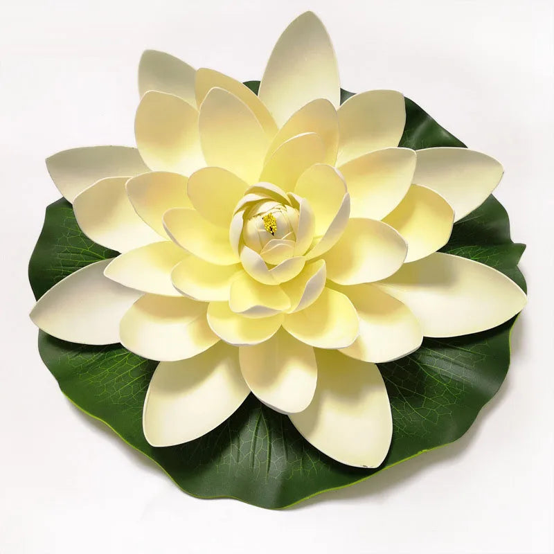 A lifelike floating lotus flower made of pale yellow petals resting on a dark green leaf.