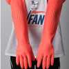 A pair of bright orange silicone scrubbing dishwashing gloves worn on the hands against a white shirt.
