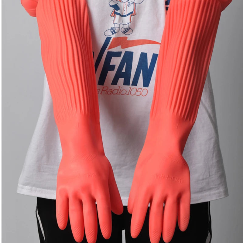 A pair of bright orange silicone scrubbing dishwashing gloves worn on the hands against a white shirt.