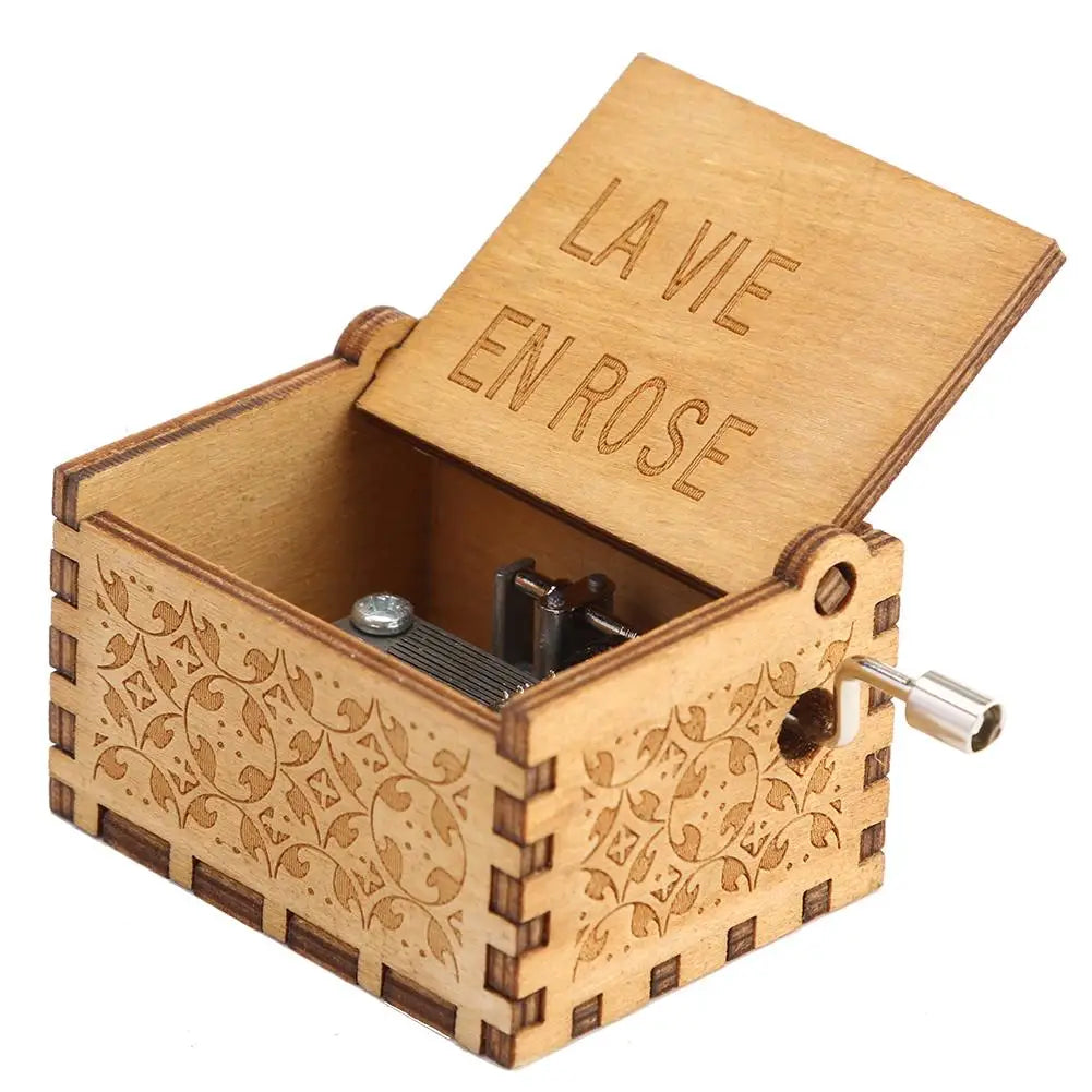 A wooden music box with a lid engraved 'LA VIE EN ROSE' and a crank mechanism.
